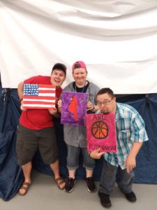 Three people with disabilities showing off their paintings