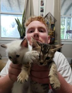 A man with a disability holds up two kittens